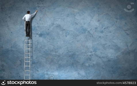 businessman drawing diagram. businessman standing on ladder drawing diagrams and graphs
