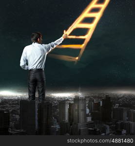 Businessman drawing ladder. Image of young businessman standing with back drawing ladder