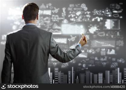 Businessman drawing plan. Rear view of businessman touching digital screen