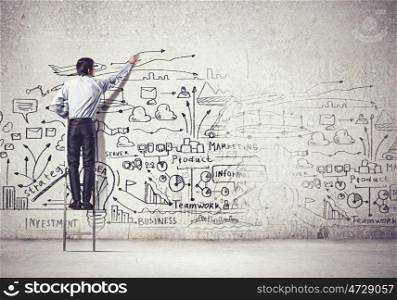 Businessman drawing sketch. Back view of businessman drawing sketch on wall
