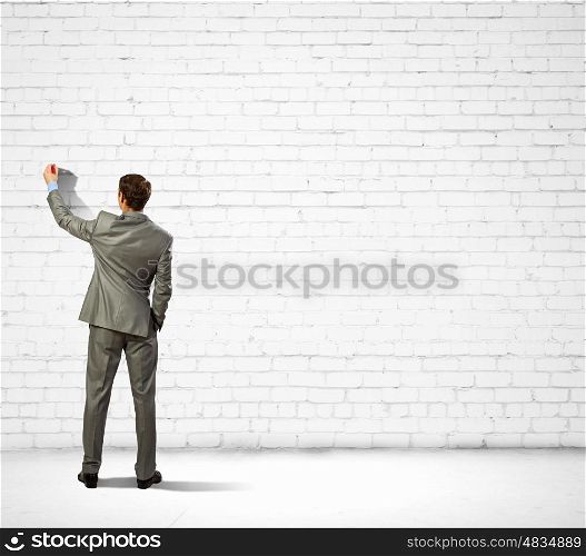 Businessman drawing sketches on wall. Back view image of businessman drawing on wall