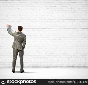 Businessman drawing sketches on wall. Back view image of businessman drawing on wall