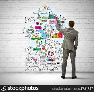 Businessman drawing sketches on wall. Back view image of businessman drawing sketches on wall