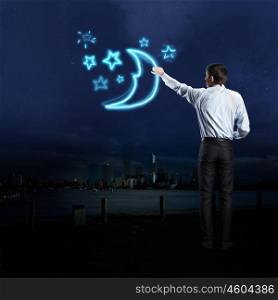 Businessman draws a moon and stars. Businessman draws a moon and stars in the dark sky