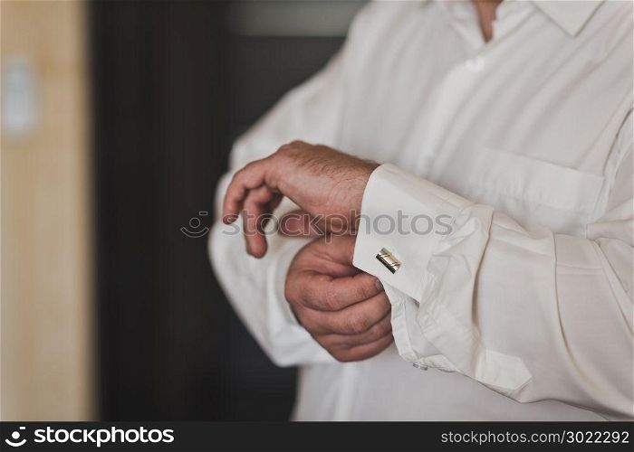 Businessman dressed for a meeting.. Strong business man buttons cuff link on the sleeve of a white shirt 499.