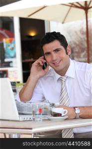 Businessman drinking an expresso in a cafe while talking on a cellphone