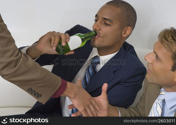 Businessman drinking beer with two businessmen shaking hands beside him