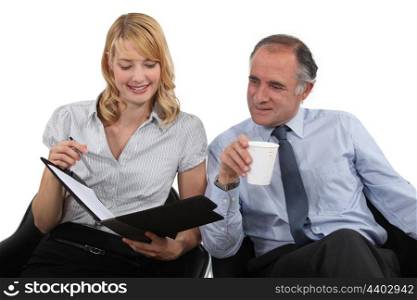 businessman drinking coffee and talking to his assistant