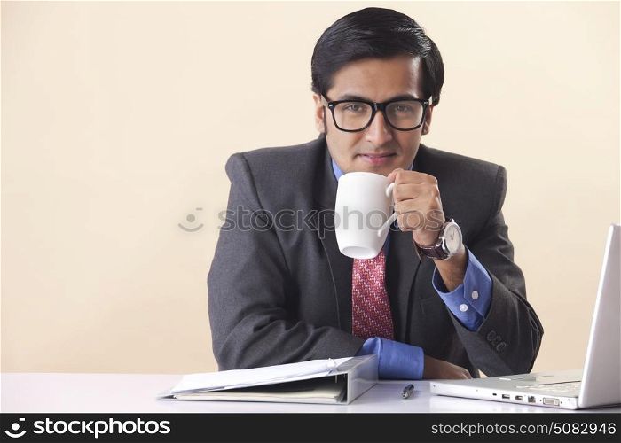 Businessman drinking coffee at desk