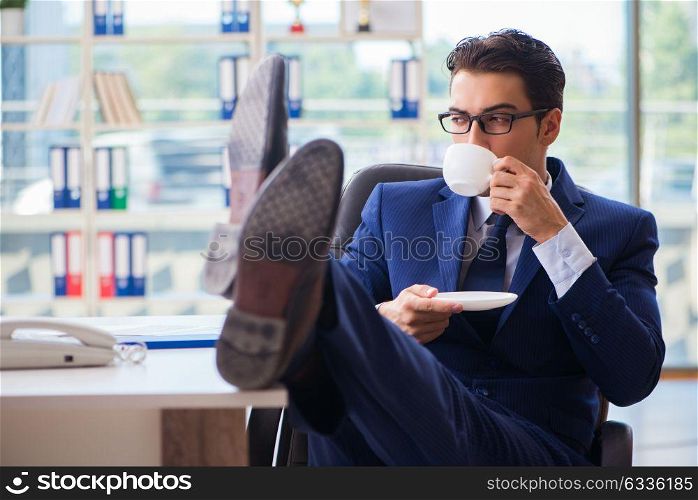 Businessman drinking coffee in the office during break. The businessman drinking coffee in the office during break