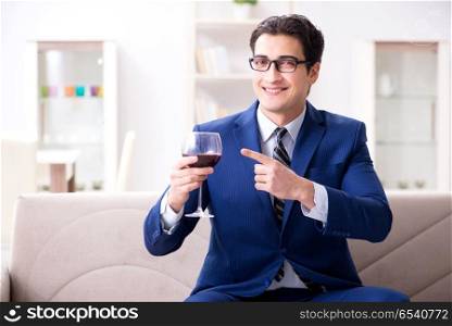 Businessman drinking wine sitting at home