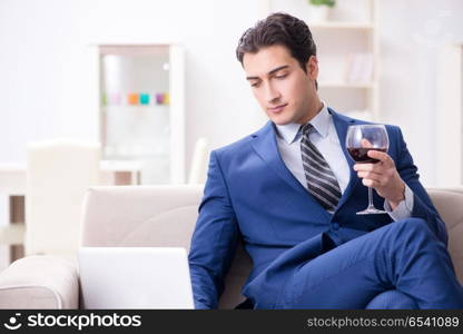 Businessman drinking wine sitting at home