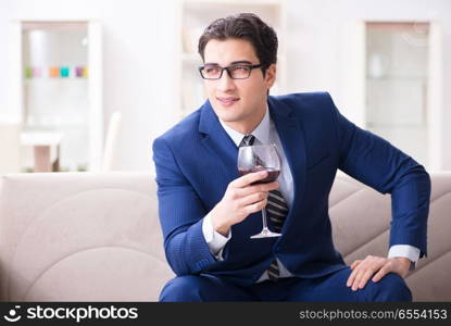 Businessman drinking wine sitting at home