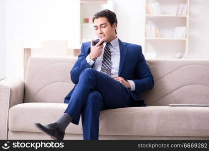 Businessman drinking wine sitting at home