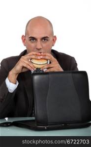 Businessman eating a burger at his desk