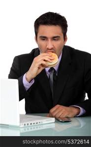 businessman eating a hamburger at his desk