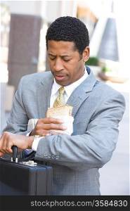 Businessman eating sandwich and checking time