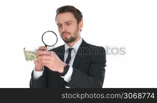 Businessman examining a dollar banknote with a magnifying glass to check that it is not counterfeit, isolated on white