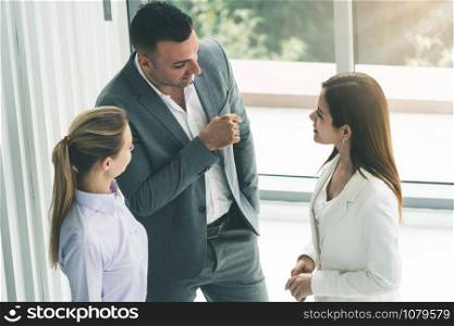 Businessman executive is in meeting discussion with colleague businesswomen in modern workplace office. People corporate business team concept.