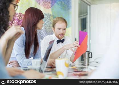Businessman explaining documents to female colleagues in creative office