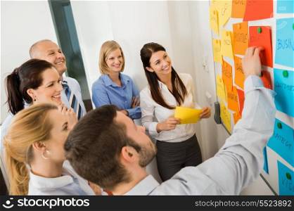 Businessman explaining labels on whiteboard to colleagues in meeting