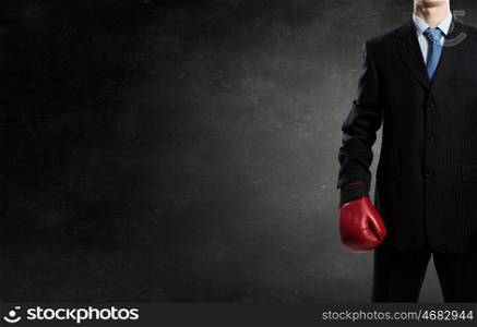 Businessman fighter in boxing gloves. Young businessman in red boxing gloves on cement background