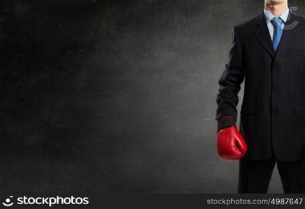 Businessman fighter in boxing gloves. Young businessman in red boxing gloves on cement background