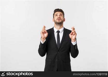 Businessman fingers cross on copy space. Handsome young man in suit looking at camera while standing against white background. Businessman fingers cross on copy space. Handsome young man in suit looking at camera while standing against white background.