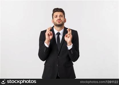 Businessman fingers cross on copy space. Handsome young man in suit looking at camera while standing against white background. Businessman fingers cross on copy space. Handsome young man in suit looking at camera while standing against white background.