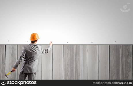 Businessman fixing banner. Rear view of businessman fixing blank white banner on wall