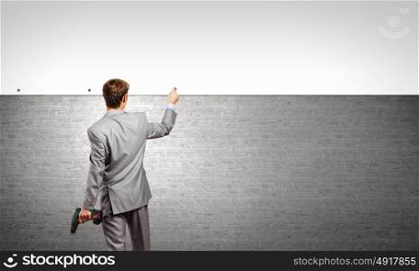 Businessman fixing banner. Rear view of businessman fixing blank white banner on wall