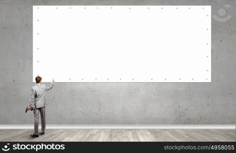 Businessman fixing banner. Rear view of businessman fixing blank white banner on wall