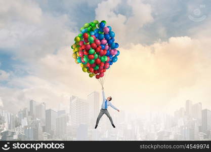 Businessman flies in sky. Young successful businessman flies on bunch of colorful balloons