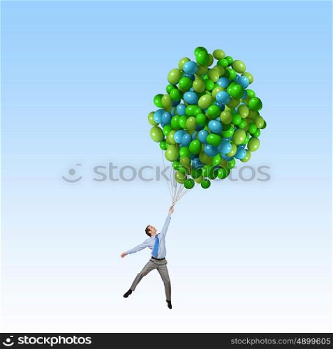Businessman flies in sky. Young successful businessman flies on bunch of colorful balloons
