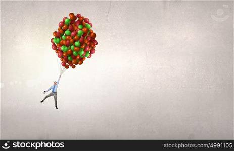 Businessman flies in sky. Young successful businessman flies on bunch of colorful balloons
