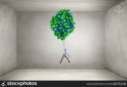 Businessman fly on balloons. Young successful businessman fly on bunch of colorful balloons