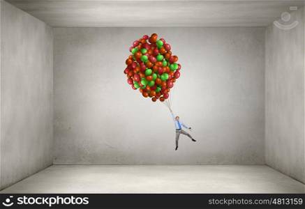Businessman fly on balloons. Young successful businessman fly on bunch of colorful balloons