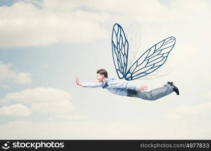 Businessman flying high. Young businessman with drawn wings flying in sky