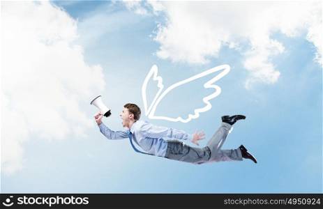 Businessman flying high. Young businessman with wings flying in sky and talking in megaphone
