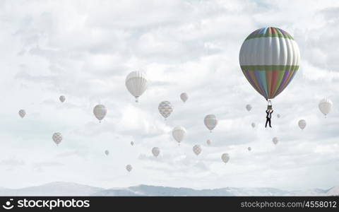 Businessman flying in search of ideas hanging on balloon. Search for new business ideas