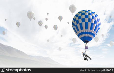 Businessman flying in search of ideas hanging on balloon. Search for new business ideas