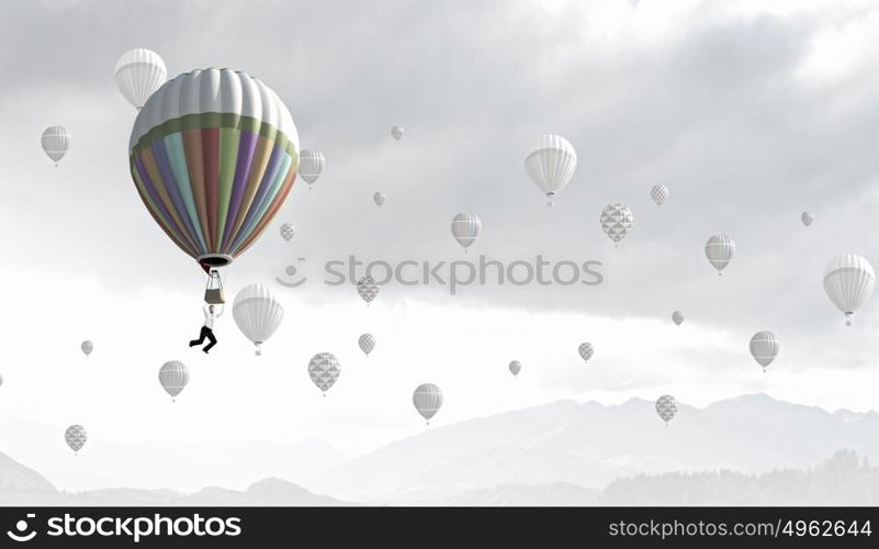 Businessman flying in search of ideas hanging on balloon. Search for new business ideas
