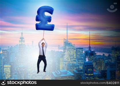 Businessman flying on british pound sign inflatable balloon