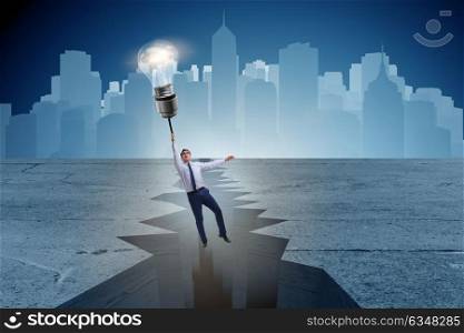 Businessman flying over gap on light bulb balloon