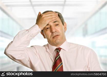 Businessman gestures with a headache at the office
