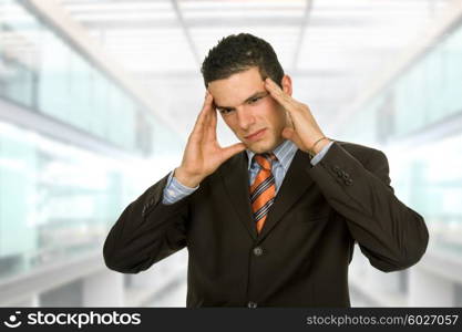 Businessman gestures with a headache, at the office