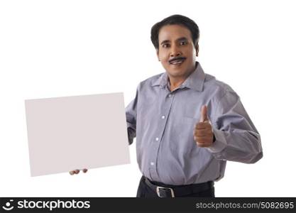 Businessman gesturing thumbs up with blank sign on white background