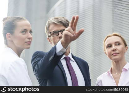 Businessman gesturing to businesswomen against office