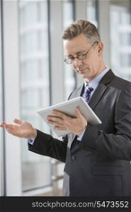 Businessman gesturing while using tablet PC in office