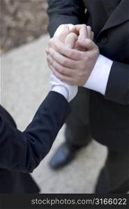 Businessman giving a handshake to a businesswoman and holding his hand with both of his hands in comfort and consulation